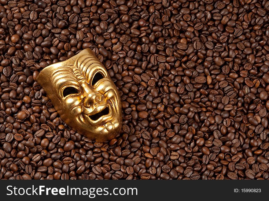Smiling gold mask on coffee roasted background. Smiling gold mask on coffee roasted background.