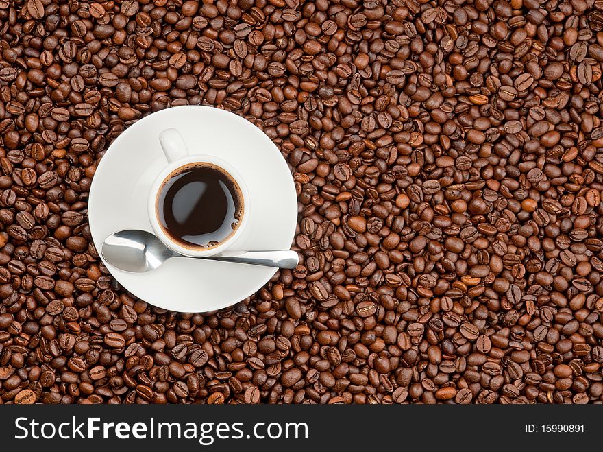 Black espresso coffee in white cup stands on coffee beans background. Black espresso coffee in white cup stands on coffee beans background.