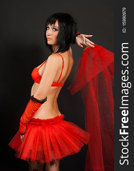 Beautiful dark-haired girl in a red wedding dress isolated on black background in studio. Beautiful dark-haired girl in a red wedding dress isolated on black background in studio