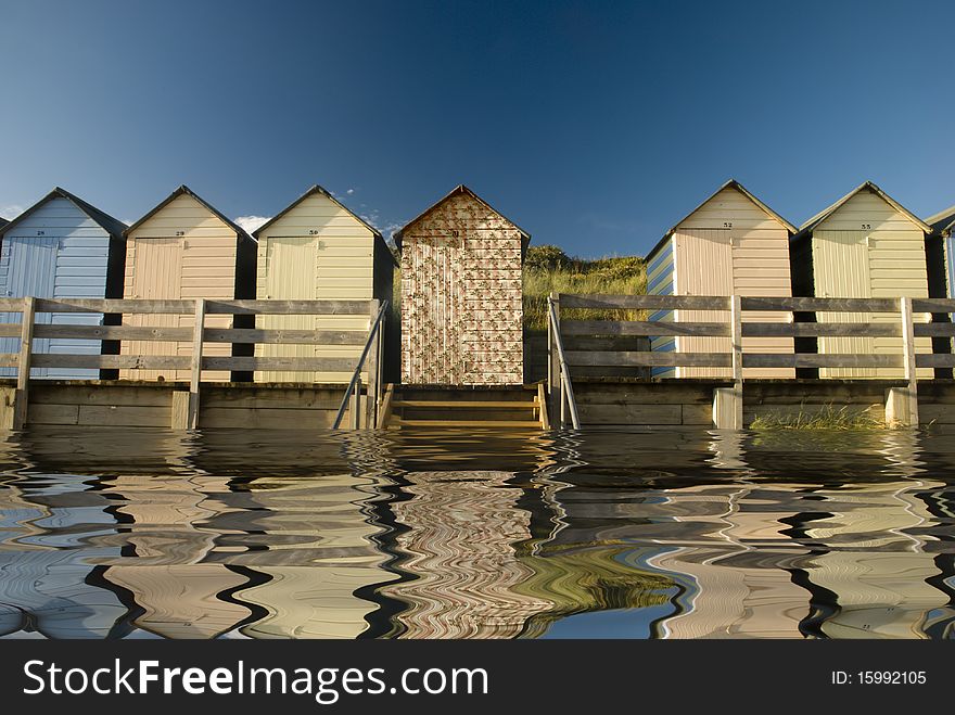 Beach huts reflected in water.One individual hut wallpapered
