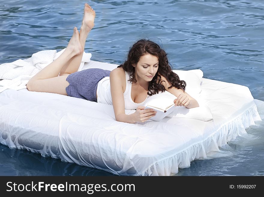 Beautiful young woman lying on the white bed in the sea. Beautiful young woman lying on the white bed in the sea