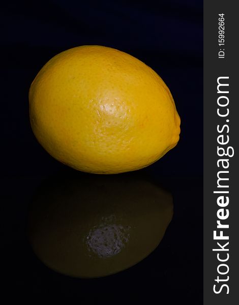 Yellow lemon on black background with reflection