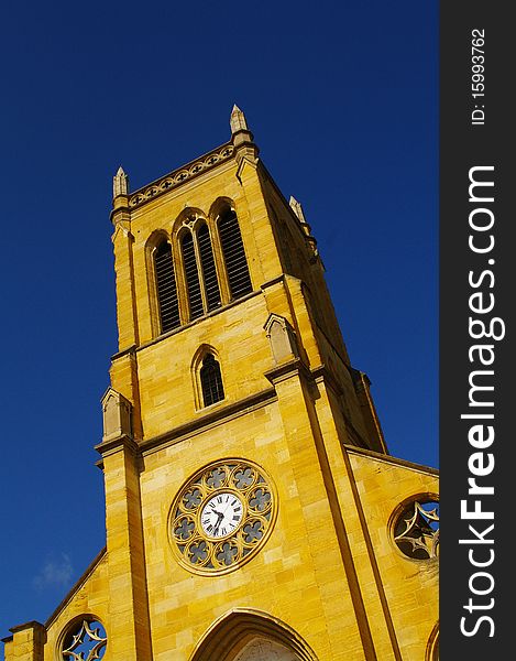 Yellow limestone church of roanne against blue sky in france