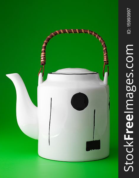 White porcelain teapot with  wooden handle on  bright green background. White porcelain teapot with  wooden handle on  bright green background