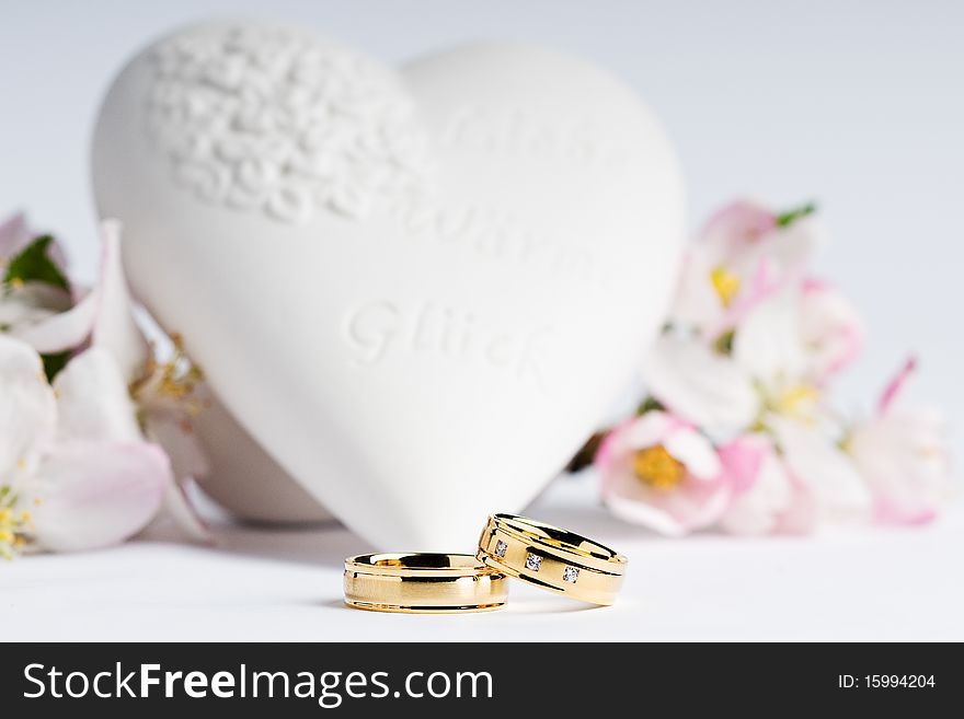 Two wedding rings with a heart and flowers in the background