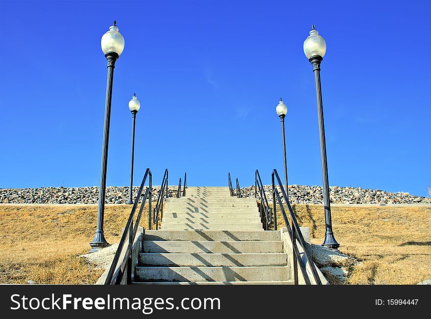 A stairway leading up to an unknown location with light poles on both sides. A stairway leading up to an unknown location with light poles on both sides.