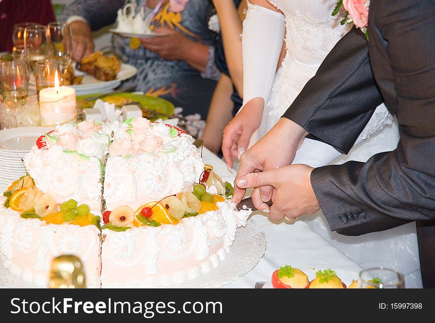 Just married are cuting the wedding cake on the table