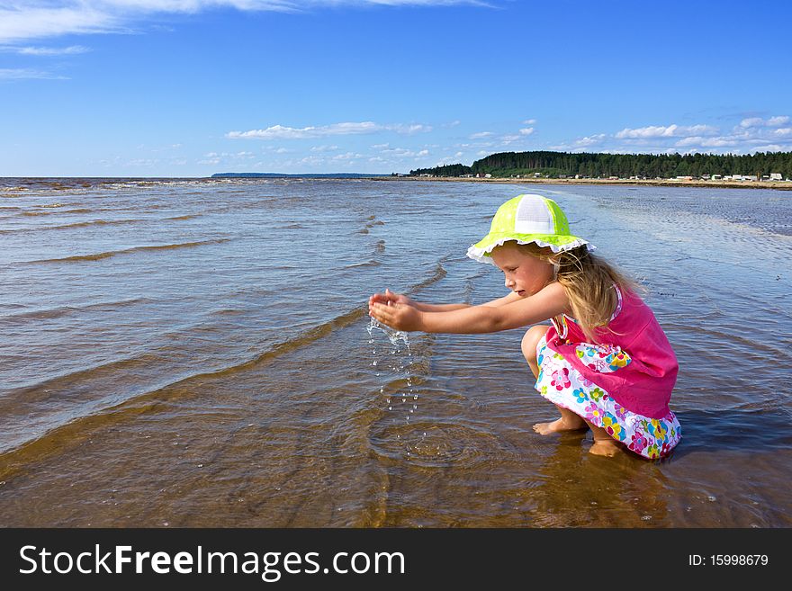 The little girl igret water on the beach. The little girl igret water on the beach.