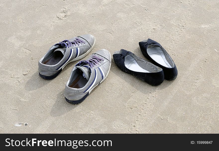 Male and female shoes on beach sand