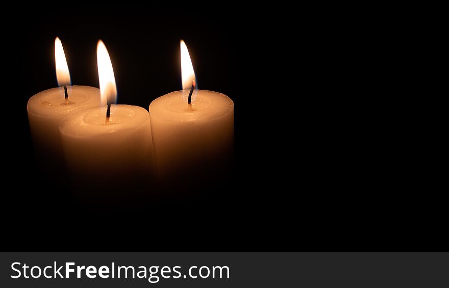 Burning candles on a black background with space to put any text