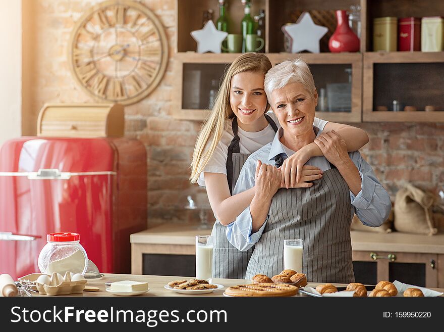 Young Woman Hugging Aged Lady At Kitchen