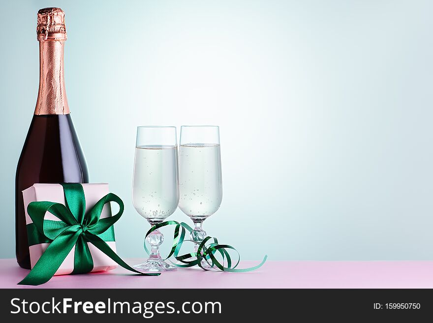 Two glasses of sparkling wine, champagne bottle and gift box in green and mint colors, copy space