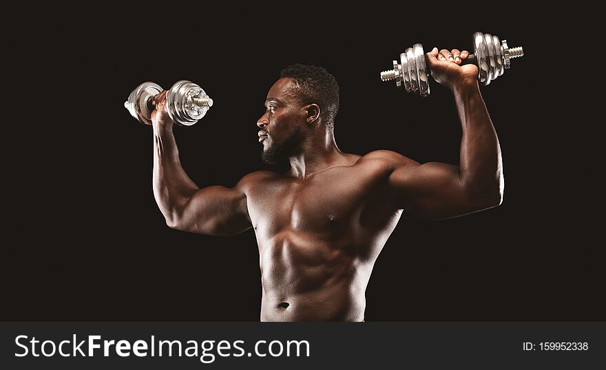 African bodybuilder working out, pushing barbells up