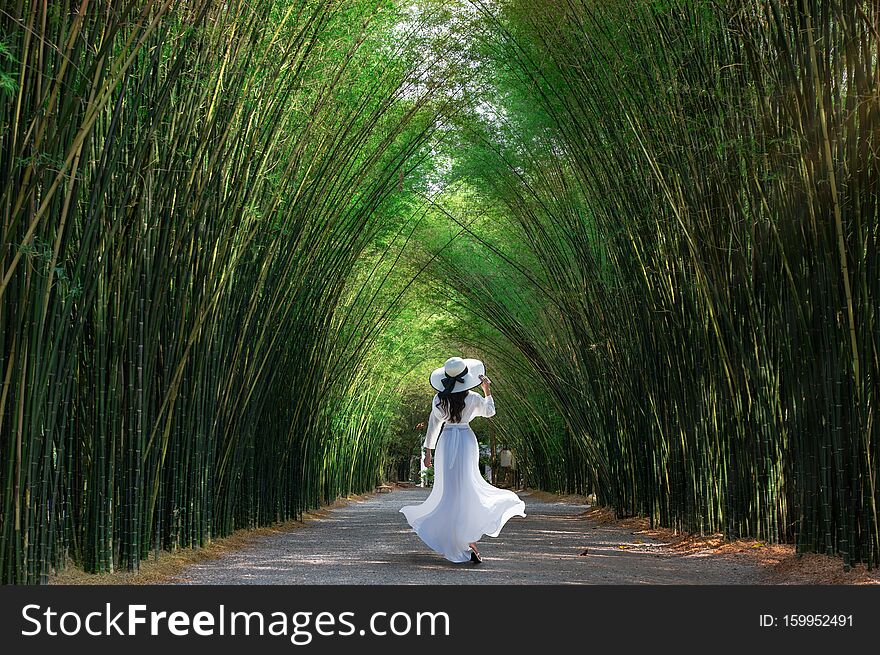 Asian woman traveler at green bamboo tunnel at Chulabhorn wanaram temple is a tourist attraction of the Nakhon Nayok Province, Thailand.