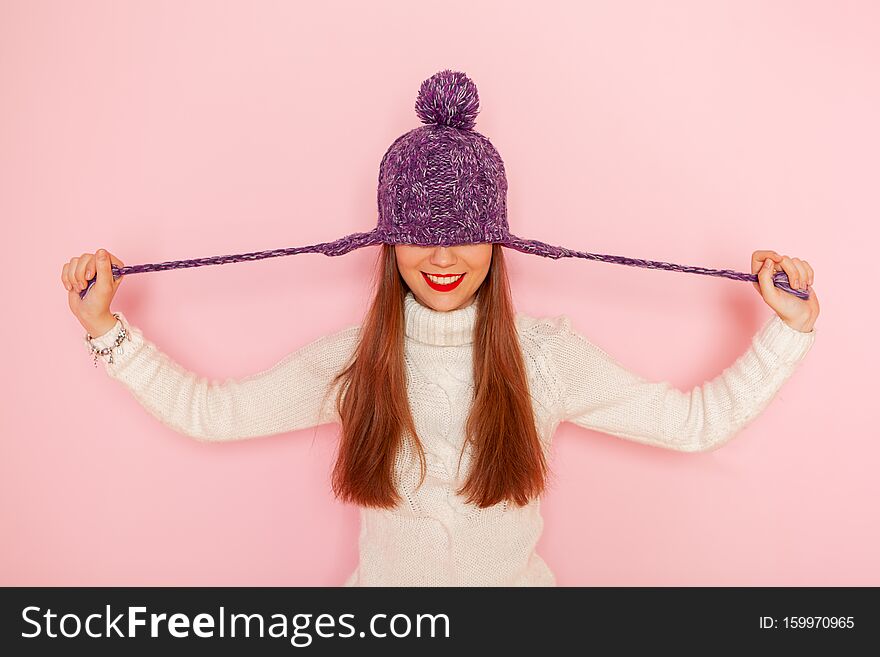 Fashion happy young woman in knitted hat and sweater having fun over pink background. Smiling. Red lips