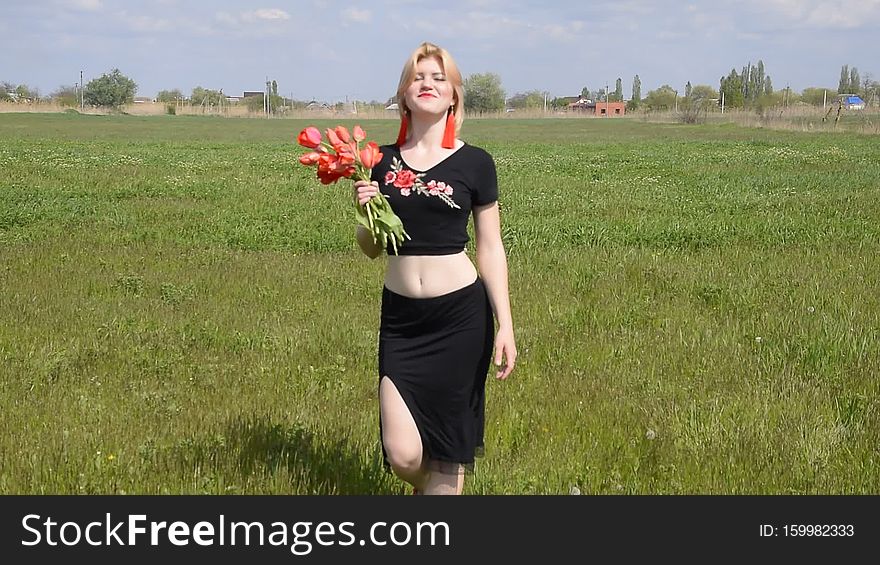 Young woman with a bouquet of tulips in the field.