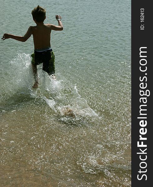 Young boy running into the ocean with a big splash. Young boy running into the ocean with a big splash