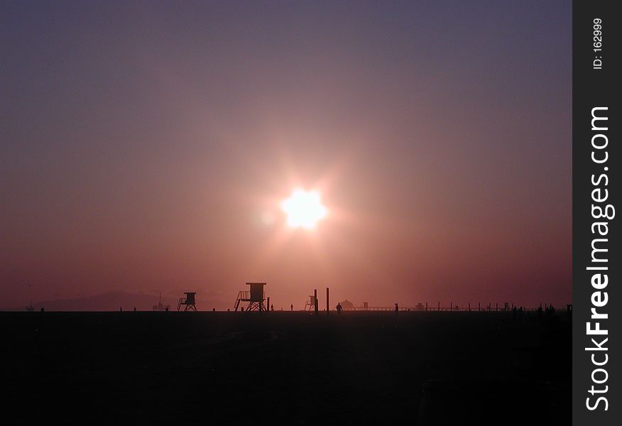 A sunset on the beach over lifeguard towers. A sunset on the beach over lifeguard towers