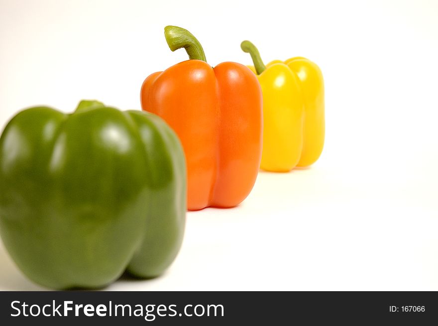 Green, yellow and orange paprika on a white background.