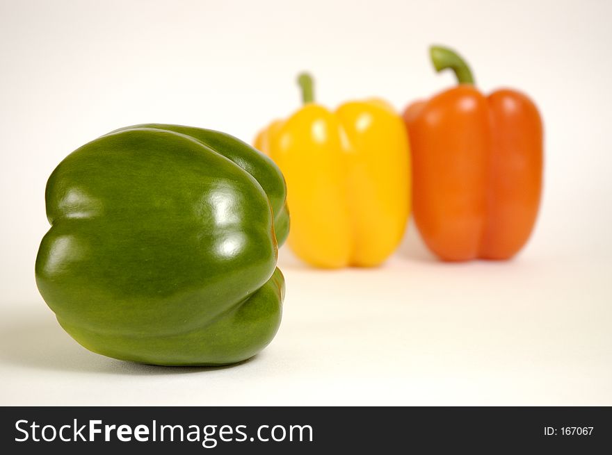 Green, yellow and orange paprika on a white background.