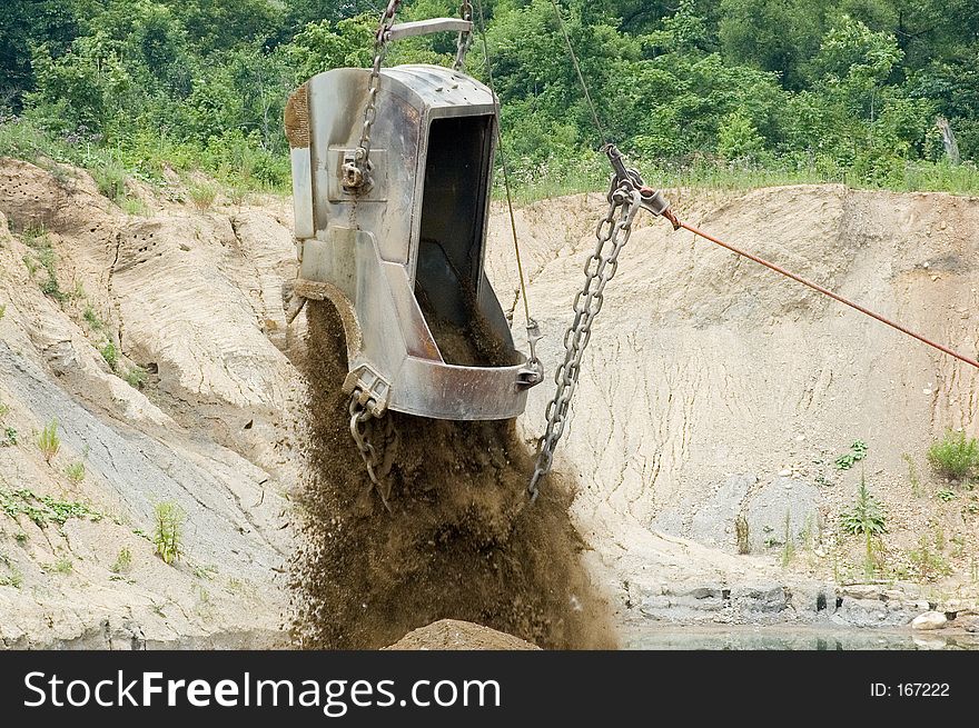 A large excavating bucket being dumped. A large excavating bucket being dumped