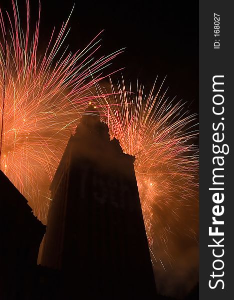 A tall building is silhouetted by bursts of fireworks. A tall building is silhouetted by bursts of fireworks