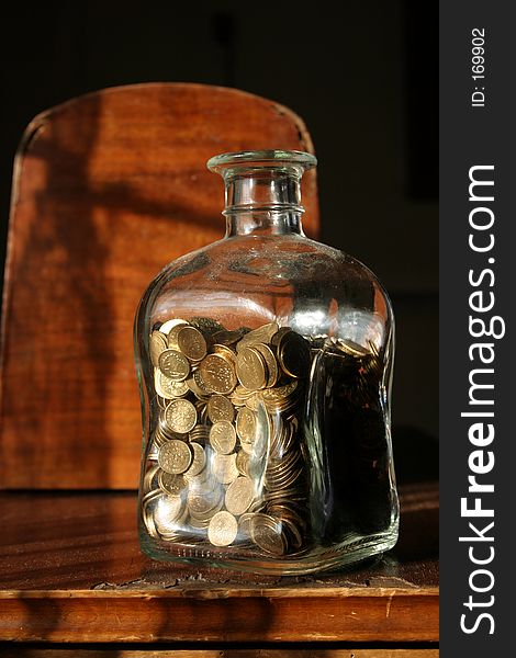 Glass jar with coins paced on a dark background