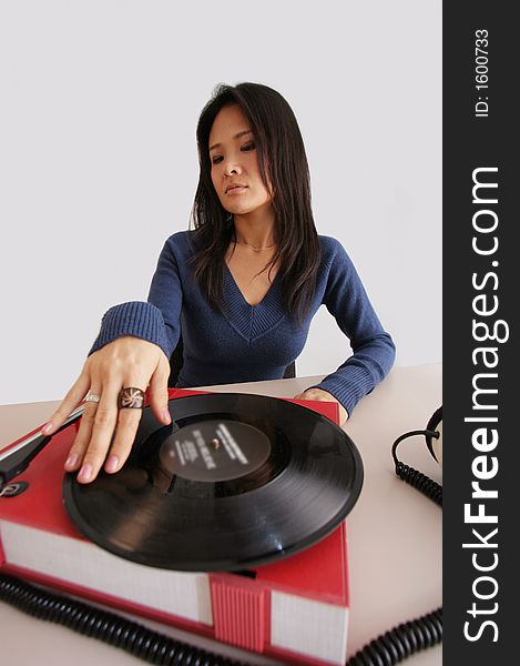 Studio shot of japanese woman looking at retro record player and headphones. Studio shot of japanese woman looking at retro record player and headphones
