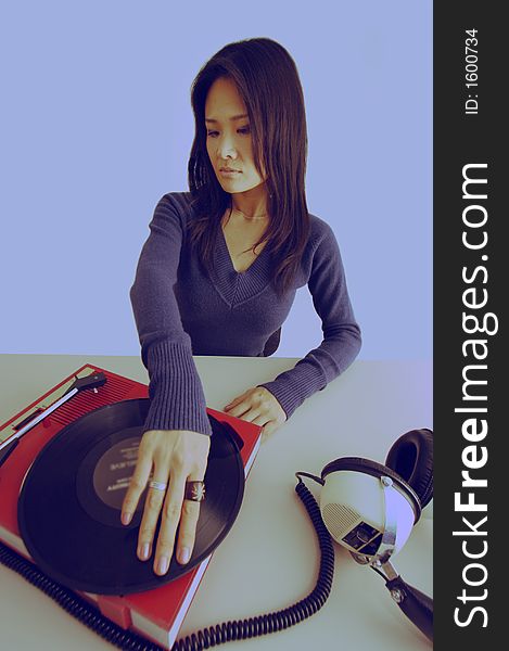 Studio shot of japanese woman looking at retro record player and headphones. Studio shot of japanese woman looking at retro record player and headphones