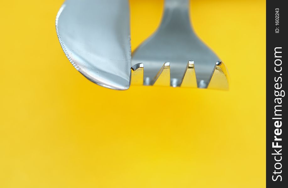 Abstract shot with a fork and a knife in vivid yellow background. Abstract shot with a fork and a knife in vivid yellow background