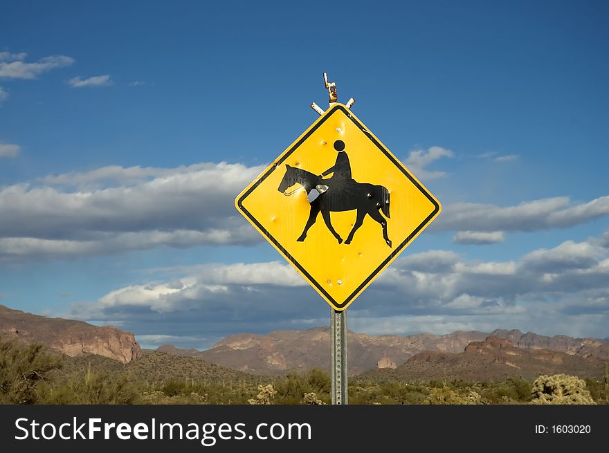 Blue sky and clouds of rural desert landscape with horse crossing sign