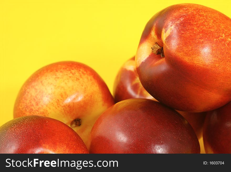 Colorful nectarines (peaches) over yellow background. Closeup. Colorful nectarines (peaches) over yellow background. Closeup.