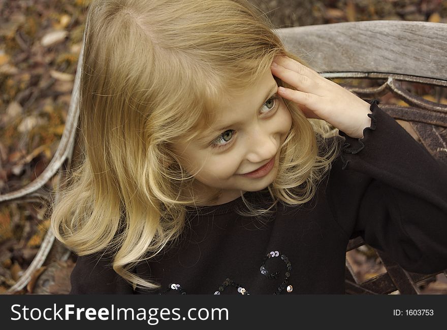 Cute little girl posing on a bench in autumn. Cute little girl posing on a bench in autumn