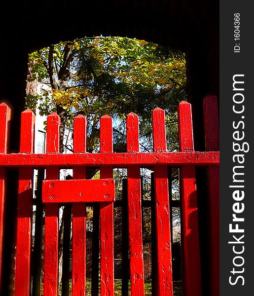 A red picket fence frames a lush courtyard behind