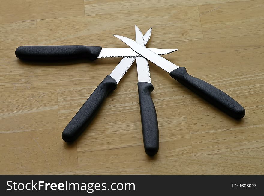 Set of four steak knives arranged against a butcher block tabletop