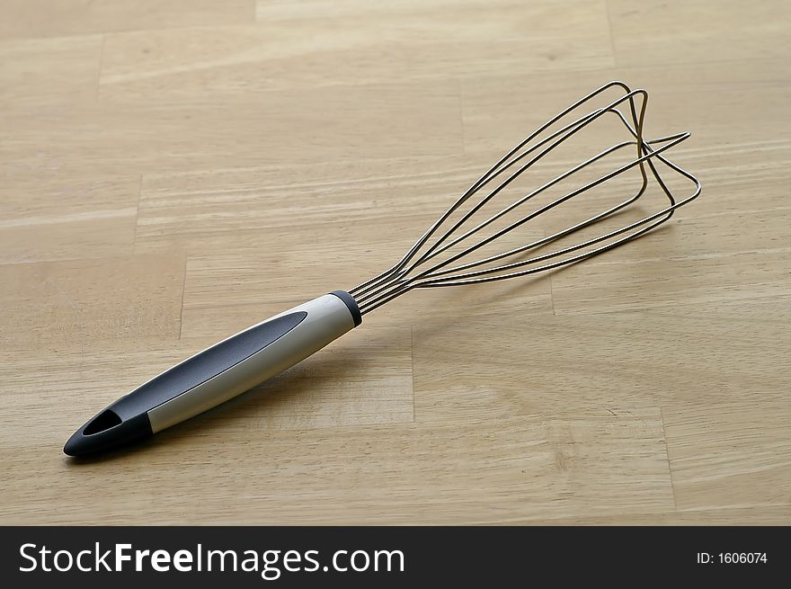 Closeup of a kitchen whisk against a butcher block tabletop