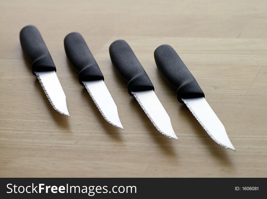 Set of four serrated steak knives against a butcher block tabletop