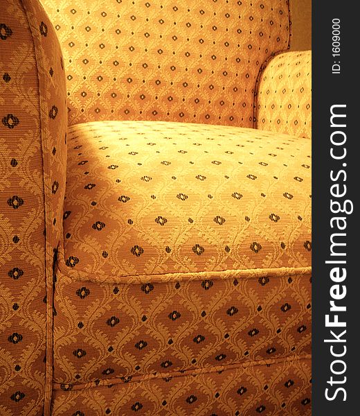 A yellow patterned overstuffed armchair from an extreme angle. A yellow patterned overstuffed armchair from an extreme angle