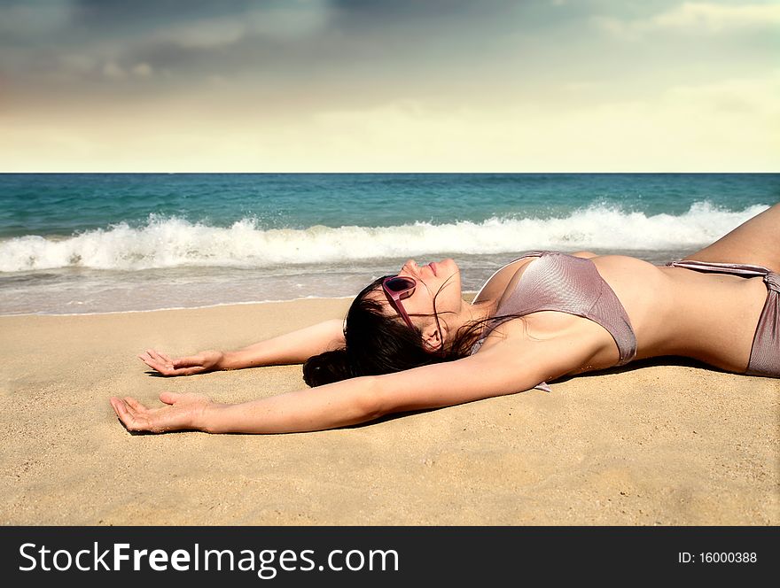 Beautiful woman lying on a beach and sunbathing