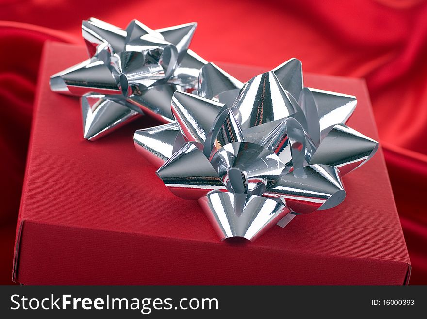 Red gift box with silver bows.Studio shot on a red background.