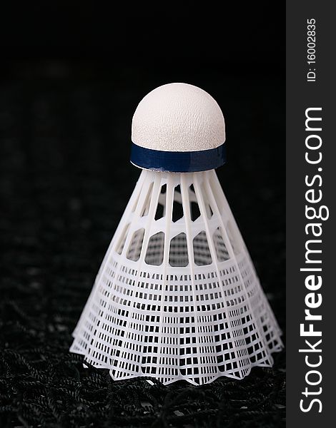 Close-up of a white synthetic shuttlecock on a badminton net.