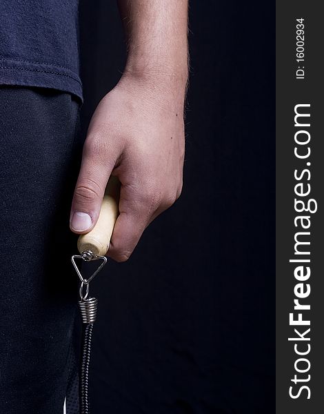 Human hand holding a jump rope on a black background.