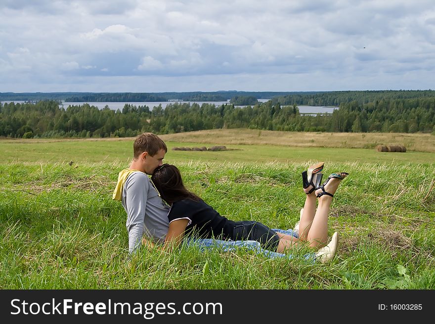Young couple sits on a grass and looks afar. Young couple sits on a grass and looks afar