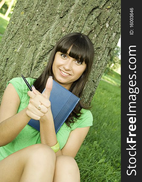 Young beautiful woman in a park with a notebook. Young beautiful woman in a park with a notebook.