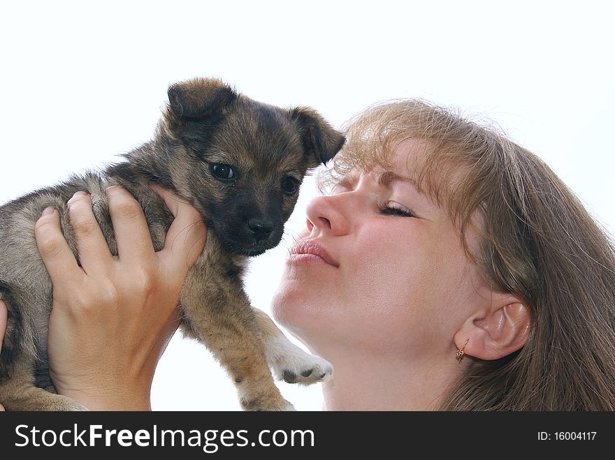 The woman holds a puppy in hands and brings it to the face