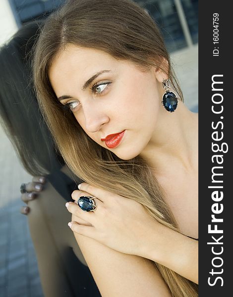 Portrait of elegantly beautiful young woman. The girl beautiful jewelry, ring and earrings with large blue stones. Portrait of elegantly beautiful young woman. The girl beautiful jewelry, ring and earrings with large blue stones