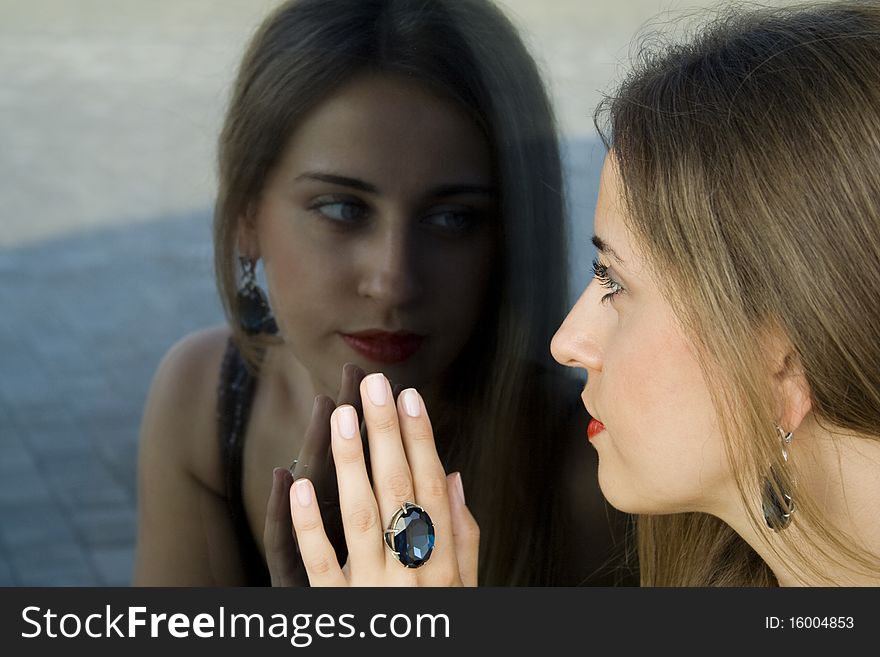Portrait of elegantly beautiful young woman. The girl beautiful jewelry, ring and earrings with large blue stones. Portrait of elegantly beautiful young woman. The girl beautiful jewelry, ring and earrings with large blue stones