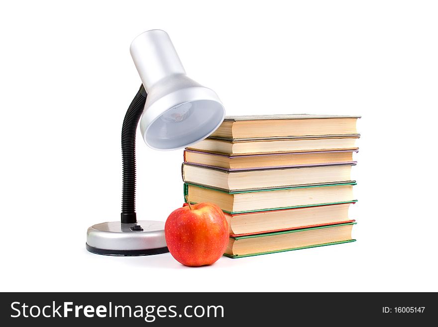 Table lamp, apple and books on white background