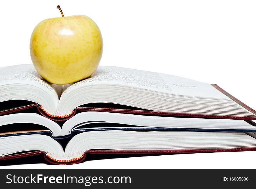 Stack of books and green apple on a white background