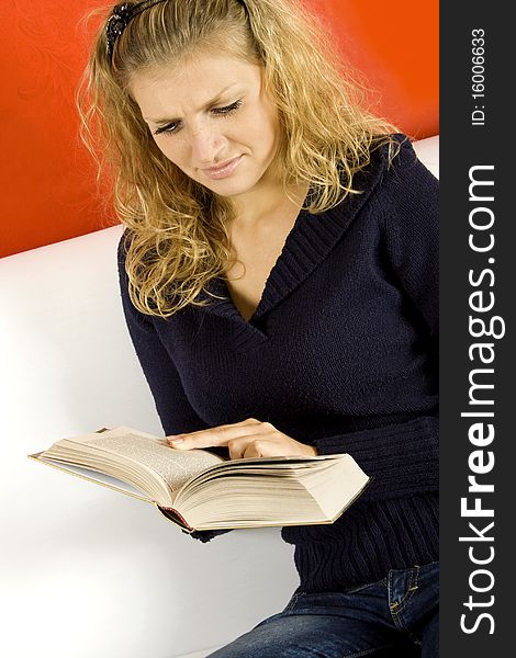 Young woman sitting on the sofa reading a book. Young woman sitting on the sofa reading a book